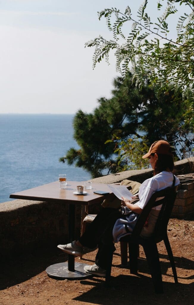 woman sitting at table enjoying view of sea.